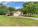 Side view of home with garage and covered parking, surrounded by green lawn at 201 W New York Ave, Orange City, FL 32763