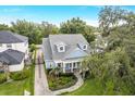 Aerial view of a beautiful blue home with manicured landscaping, brick drive, mature trees, and a lush green lawn at 2401 Lafayette Ave, Winter Park, FL 32789