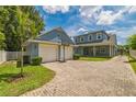 View of the driveway and garage of a two-story blue house with a brick driveway and basketball hoop at 2401 Lafayette Ave, Winter Park, FL 32789