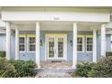 View of the house and porch with white columns, yellow accents, and brick walkway leading to the front door at 2401 Lafayette Ave, Winter Park, FL 32789