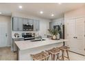 Modern kitchen with gray cabinetry, stainless steel appliances, a quartz countertop island, and stylish bar stools at 3747 King Hill Dr, Haines City, FL 33844