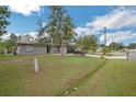 Exterior view showcasing a home's front yard, lush lawn, mature trees, and extended driveway at 107 Talavera Ln, Kissimmee, FL 34758