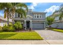 Charming two-story home boasts a stone-accented facade, gray palette, lush landscaping, and a paved driveway at 8875 Backspin Ln, Champions Gate, FL 33896
