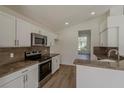 Modern kitchen featuring stainless steel appliances, granite countertops, and sleek white cabinetry at 4444 Withrowwood Ct, Orlando, FL 32837