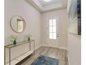 Bright entryway with wood-look tile flooring, a console table, and an elegant round mirror at 2132 Limestone Trl, Kissimmee, FL 34747