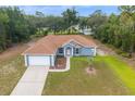 Aerial view of a one-story home with a brown roof, blue siding, an attached garage, and landscaped front yard at 8628 Sw 133Rd Lane Rd, Ocala, FL 34473