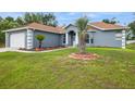Front view of a one-story gray home featuring a two car garage, and a well-manicured lawn at 8628 Sw 133Rd Lane Rd, Ocala, FL 34473