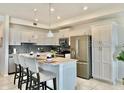 Modern kitchen with stainless steel appliances, a breakfast bar, and sleek white cabinetry at 4751 Clock Tower Dr # 307, Kissimmee, FL 34746