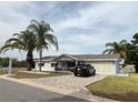 Inviting single-story home featuring a manicured lawn, brick driveway and attached garage at 17569 Se 107Th Ct, Summerfield, FL 34491