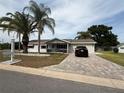 Well-maintained single-story home boasting a brick driveway, lush lawn, and attached garage at 17569 Se 107Th Ct, Summerfield, FL 34491
