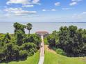 Scenic waterfront view featuring a wooden walkway leading to a charming gazebo surrounded by lush greenery at 297 Beacon Pointe Dr, Ocoee, FL 34761