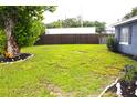 Spacious backyard with lush green grass, a privacy fence, and mature trees, creating a serene outdoor space at 5 Moonlight Ln, Winter Haven, FL 33884