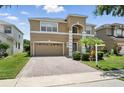 Inviting two-story tan home featuring a paved driveway, well-kept lawn, and a classic two-car garage at 5233 Los Palma Vista Dr, Orlando, FL 32837
