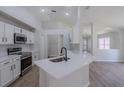 Modern white kitchen featuring stainless steel appliances, quartz countertops, and a breakfast bar at 316 Red Kite Dr, Groveland, FL 34736