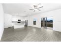 Bright, open living space with sleek flooring, modern ceiling fan, and sliding glass doors at 3808 Corsican Pl, Lake Alfred, FL 33850