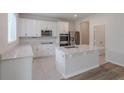 Modern kitchen with white cabinets, granite countertops, stainless steel appliances, and tile flooring at 16398 Yelloweyed Dr, Clermont, FL 34714
