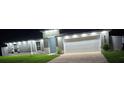 Well-lit home exterior showcasing a two-car garage and manicured front lawn at night at 10090 Se 67Th Ter, Belleview, FL 34420