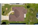 Aerial view of the well-maintained home with a brown roof, green lawn, and long driveway at 1032 Kelsea Cir, The Villages, FL 32159