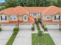 Aerial view of townhomes with red tile roofs, garages, and green lawns, surrounded by lush trees at 2256 Wekiva Village Ln, Apopka, FL 32703