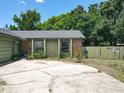 Home exterior featuring stone details, cracked driveway, manicured shrubs, and a wooden privacy fence at 3300 Glen Village Ct, Orlando, FL 32822