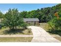 Single-story home on a cracked driveway framed by mature trees and greenery, with hints of blue sky above at 3300 Glen Village Ct, Orlando, FL 32822