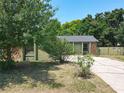 A single story home with stone facade and cracked driveway is surrounded by lush, mature trees at 3300 Glen Village Ct, Orlando, FL 32822