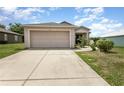 Long concrete driveway leading up to a two car garage attached to this single story home at 3235 Grand Pines Dr, Lakeland, FL 33810