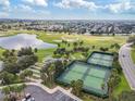Aerial view showcasing community amenities, including tennis courts, a lake, and lush landscaping at 879 Astor Way, The Villages, FL 32162