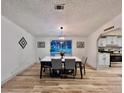 Well-lit dining area with a modern table set, view to the kitchen, and hardwood floors at 5790 Cherry Tree Dr, Lakeland, FL 33811