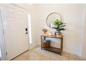 Bright foyer featuring a decor table with a round mirror, plant, and a white front door at 10274 Julia Isles Ave, Oxford, FL 34484