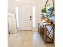 Entryway featuring a decor table with mirror, plant, and a white front door, with a leaner mirror at 10274 Julia Isles Ave, Oxford, FL 34484