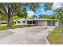 Single-story home with attached carport and enclosed porch on a large driveway surrounded by mature trees at 107 Alachua Dr, Winter Haven, FL 33884