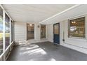 Enclosed porch with concrete floor, beadboard ceiling, screen windows and view of large green lawn at 107 Alachua Dr, Winter Haven, FL 33884
