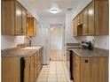 Galley style Kitchen with wooden cabinetry, white appliances, and tile flooring at 1440 12Th St, Clermont, FL 34711