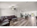 Open-concept living area with wood-look flooring, ceiling fan, and a comfortable leather sectional sofa at 231 Marion Oaks Trl, Ocala, FL 34473