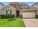 Charming single-Gathering home featuring a stone accent wall, brick driveway, manicured lawn, and a two-car garage at 1138 Fountain Coin Loop, Orlando, FL 32828