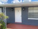 The entrance of this home showcases a stylish white front door with a glass peephole and side sconces at 119 Allen Ave, Winter Haven, FL 33880