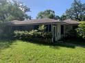 View of a single-story home with a lawn and overgrown ferns obscuring a screened-in porch on a sunny day at 550 W Oak Dr, Lakeland, FL 33803