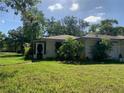 View of a single-story home with a green lawn and overgrown landscaping on a sunny day at 550 W Oak Dr, Lakeland, FL 33803