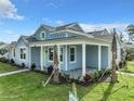 Inviting blue home featuring a charming covered porch, well-maintained lawn, and vibrant landscaping at 198 Gypsy Palace Ln, Daytona Beach, FL 32124