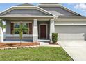 Attractive home featuring a well-manicured front yard, two-car garage, and covered entryway at 303 Briarbrook Ln, Haines City, FL 33844