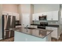 Modern kitchen with stainless steel appliances, gray countertops, island with sink, and white cabinets at 762 Ambleside Dr, Haines City, FL 33844