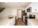 Modern kitchen featuring white cabinets, stainless steel appliances, and a spacious quartz countertop at 1229 Tidal St, Haines City, FL 33844