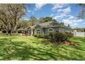 Beautifully landscaped yard with mature trees, shrubs, and green grass surrounding a charming one-story house at 1610 Sherwood Lakes Blvd, Lakeland, FL 33809