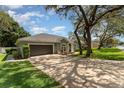 Lovely one-story home with a spacious driveway surrounded by mature trees and lush green grass at 1610 Sherwood Lakes Blvd, Lakeland, FL 33809