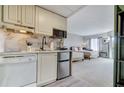 Kitchenette with white cabinets, stainless steel mini fridge, and view into the bedroom with two beds at 6165 Carrier Dr # 1309, Orlando, FL 32819