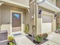 Close up of front entry way with a brown front door, flower bed and one car garage at 67 Bella Oaks Dr, Port Orange, FL 32129