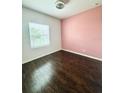 An Empty bedroom showcasing wood floors, a window, and pink accent wall at 2864 Running Brook Cir, Kissimmee, FL 34744