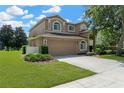 Two-story home showcasing a spacious driveway, a well-maintained lawn, and an attached two-car garage at 886 Suffolk Pl, Davenport, FL 33896