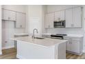 Modern kitchen features white cabinets, stainless steel appliances, gray countertops and an island with a sink at 9619 Sw 62Nd Ct, Ocala, FL 34476